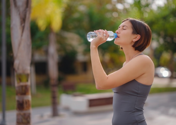 woman drinking water after jogging