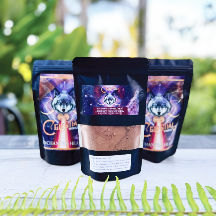 Three black resealable pouches of celestial-themed cacao powder with a wolf logo, displayed outdoors on a table with greenery in the background
