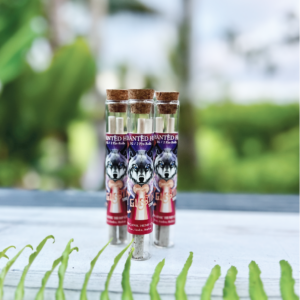 Three glass tubes with cork tops, each containing pre-rolled cones with a wolf illustration on the label, set on a white surface with green foliage in the foreground.