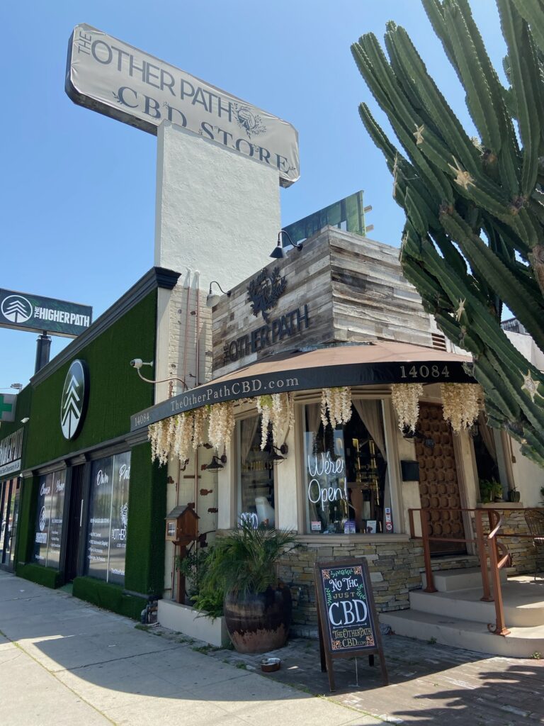 The Other Path CBD storefront in Sherman Oaks, with wood cladding, cream flowers and a cactus beside the entrance.